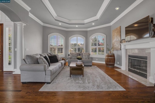 living room featuring ornamental molding, decorative columns, a tray ceiling, and dark hardwood / wood-style flooring