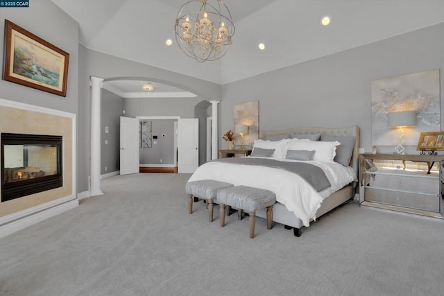 carpeted bedroom featuring ornate columns, an inviting chandelier, a multi sided fireplace, high vaulted ceiling, and crown molding