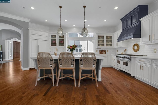 kitchen with decorative light fixtures, a center island, dark wood-type flooring, and range with two ovens