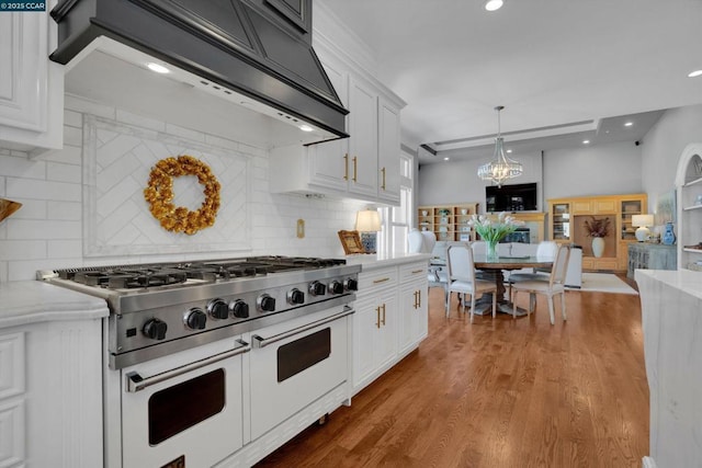 kitchen with double oven range, white cabinetry, custom range hood, and tasteful backsplash