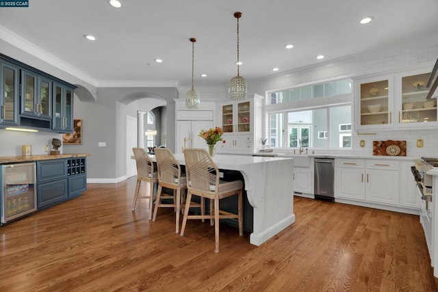 kitchen featuring pendant lighting, wine cooler, blue cabinetry, white cabinetry, and a center island