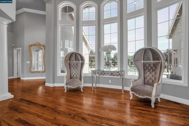 living area with a high ceiling, ornate columns, and wood-type flooring