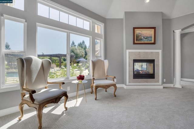 sitting room with a multi sided fireplace, light colored carpet, ornate columns, and lofted ceiling