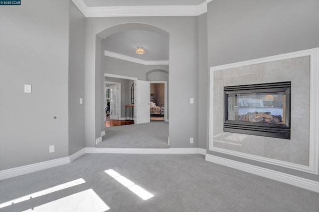 unfurnished living room featuring a multi sided fireplace, crown molding, and carpet flooring