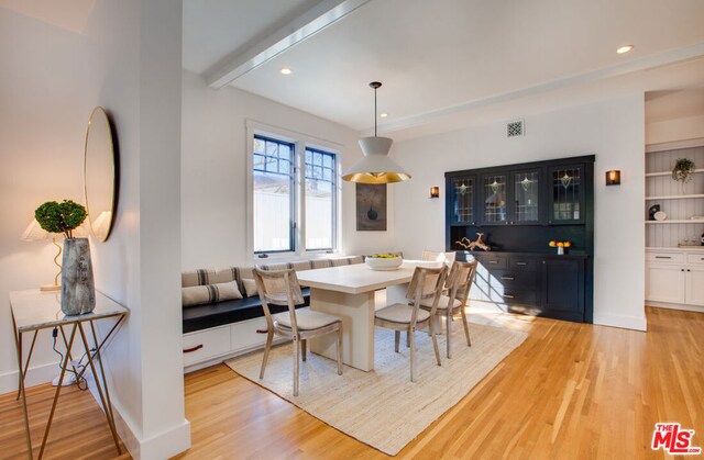 dining area with breakfast area, beamed ceiling, and light wood-type flooring