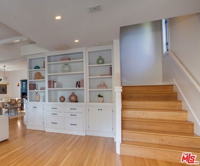 staircase featuring hardwood / wood-style flooring and built in features