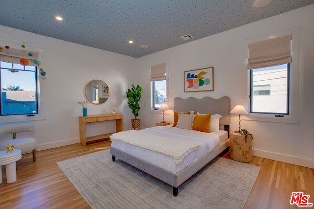 bedroom featuring multiple windows and light hardwood / wood-style flooring