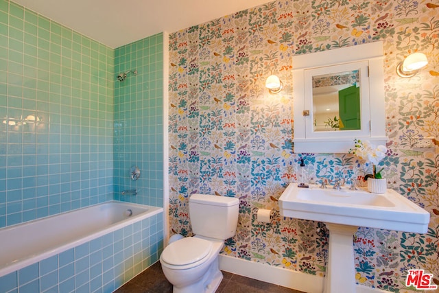 bathroom featuring tiled shower / bath combo, toilet, and tile patterned flooring