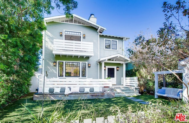 view of front of house featuring a balcony and a front yard