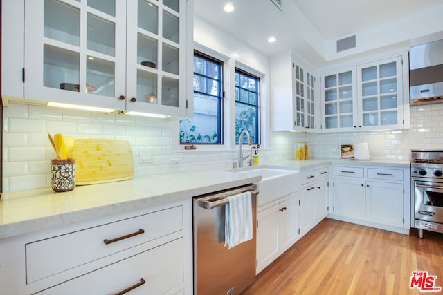 kitchen with tasteful backsplash, white cabinetry, sink, stainless steel appliances, and light stone counters