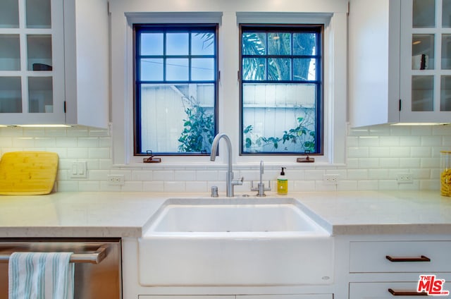 kitchen featuring sink, stainless steel dishwasher, white cabinetry, and light stone counters