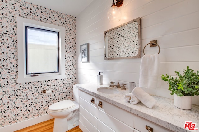 bathroom with hardwood / wood-style flooring, toilet, and vanity