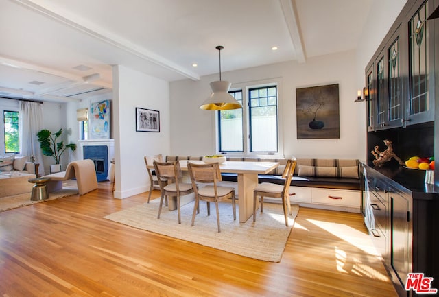 dining space featuring light hardwood / wood-style floors, a wealth of natural light, and beam ceiling