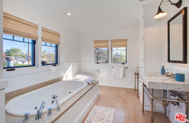 bathroom featuring vanity, tiled tub, and tile patterned flooring