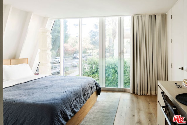 bedroom with light hardwood / wood-style floors and a wall of windows