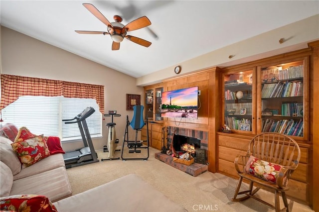 exercise area featuring vaulted ceiling, light colored carpet, ceiling fan, and a fireplace