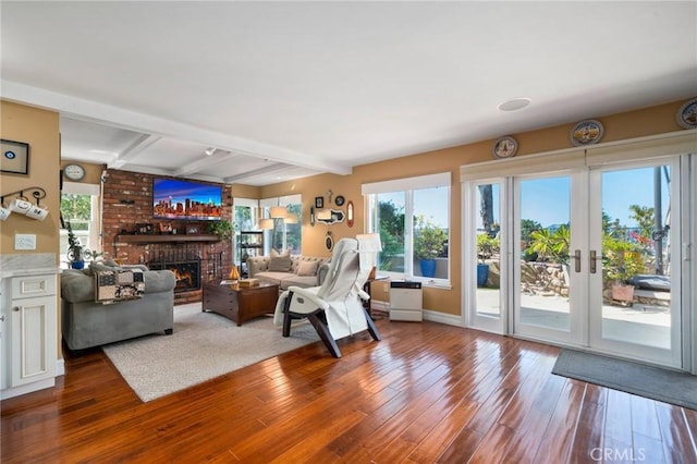 living room featuring beamed ceiling, hardwood / wood-style floors, and a brick fireplace