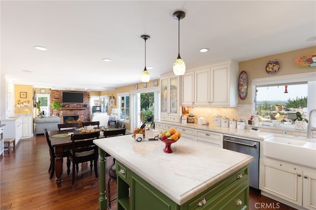 kitchen with dishwasher, sink, backsplash, a center island, and green cabinets