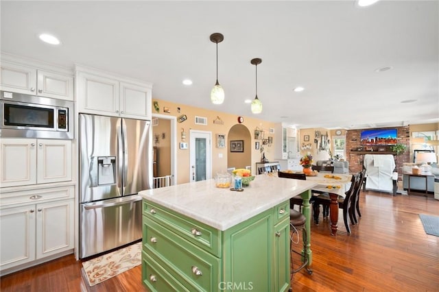 kitchen featuring a breakfast bar area, green cabinets, white cabinetry, appliances with stainless steel finishes, and a kitchen island