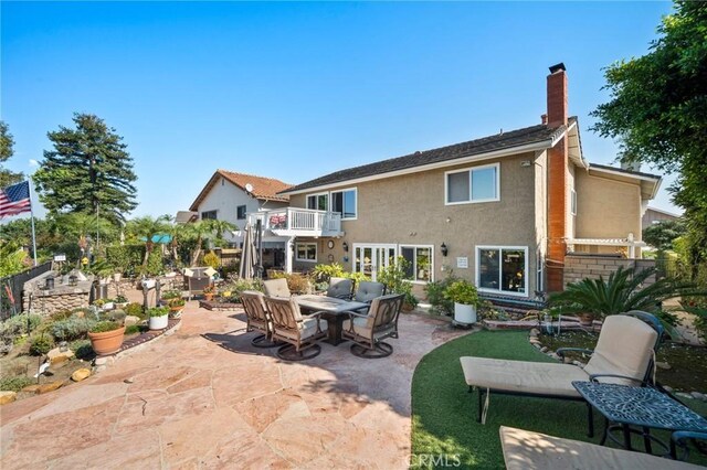 rear view of property with a patio area and a balcony