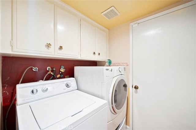 clothes washing area with cabinets and independent washer and dryer