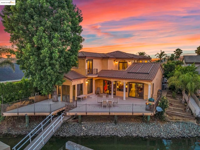 back house at dusk with a patio and solar panels