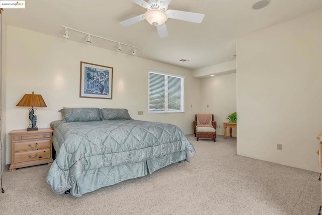 carpeted bedroom with track lighting and ceiling fan