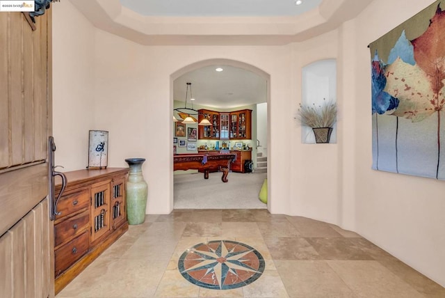 hallway featuring a raised ceiling and carpet flooring