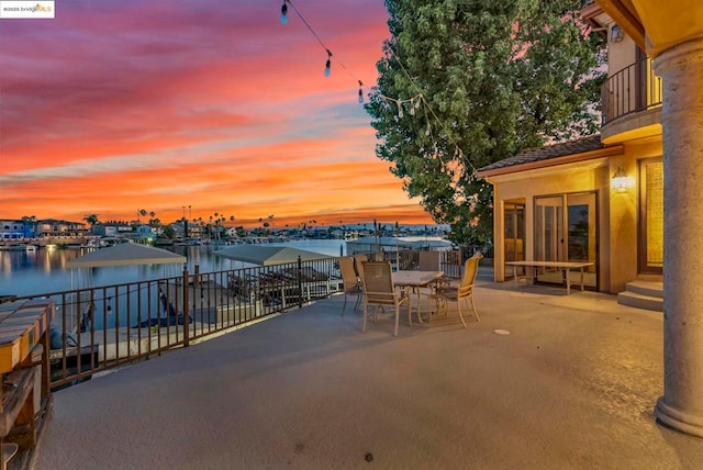 patio terrace at dusk with a balcony and a water view