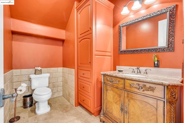 bathroom featuring toilet, tile walls, and vanity