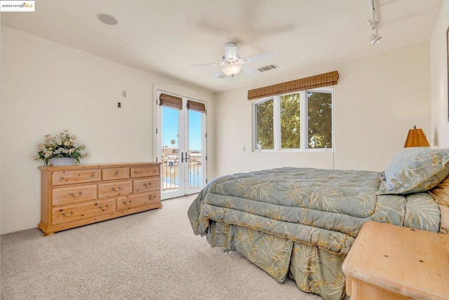 carpeted bedroom with rail lighting, multiple windows, ceiling fan, and access to outside