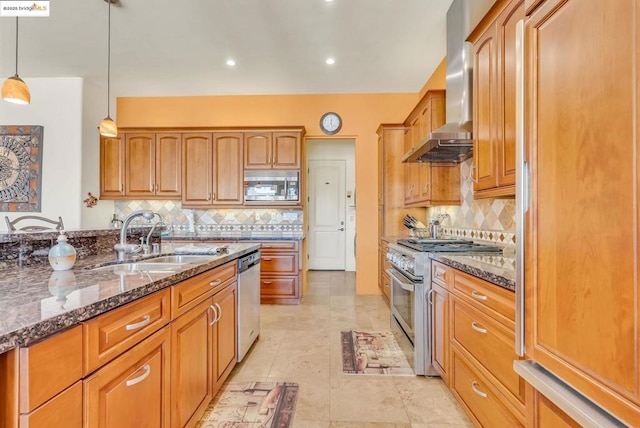 kitchen featuring pendant lighting, appliances with stainless steel finishes, sink, ventilation hood, and dark stone countertops