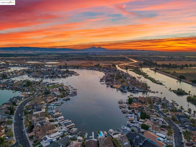 aerial view at dusk featuring a water and mountain view