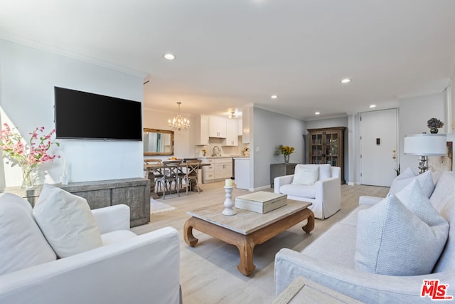 living room with light hardwood / wood-style floors, crown molding, and a chandelier