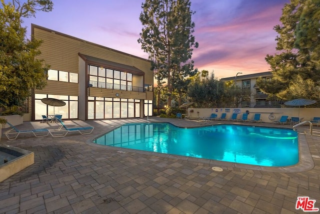 pool at dusk featuring a patio