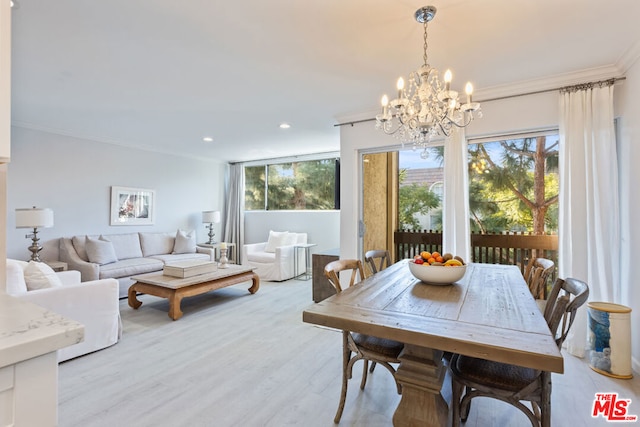 dining space with ornamental molding, a notable chandelier, and light wood-type flooring