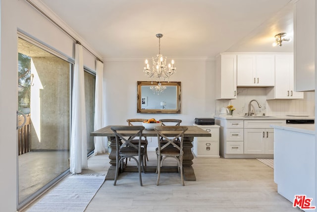 dining area featuring sink, light hardwood / wood-style flooring, ornamental molding, and a notable chandelier