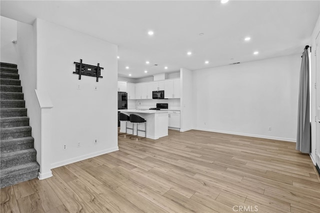 unfurnished living room featuring sink and light hardwood / wood-style floors