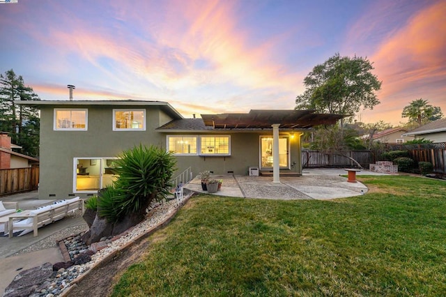 back house at dusk with a yard and a patio