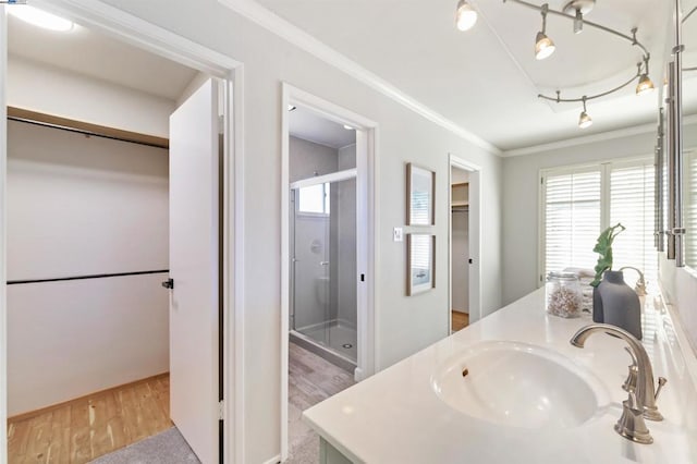 bathroom featuring hardwood / wood-style flooring, vanity, ornamental molding, and a shower with shower door