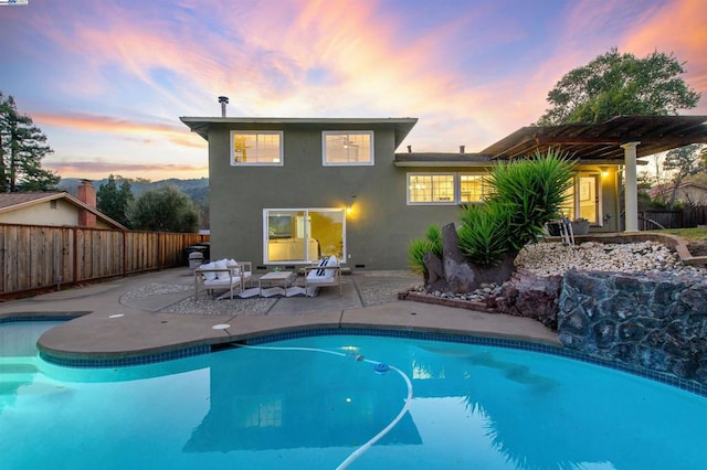 pool at dusk featuring an outdoor living space, a pergola, and a patio