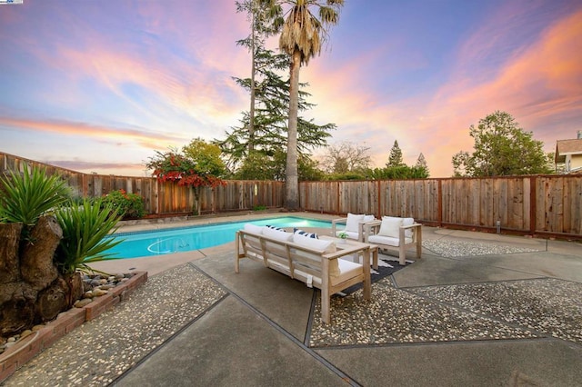 pool at dusk with outdoor lounge area and a patio