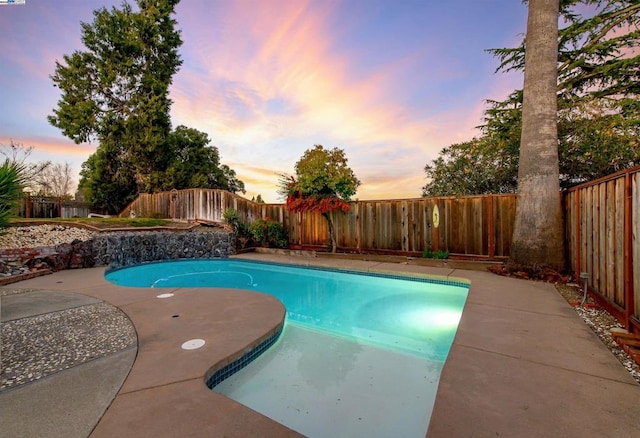 pool at dusk featuring a patio area