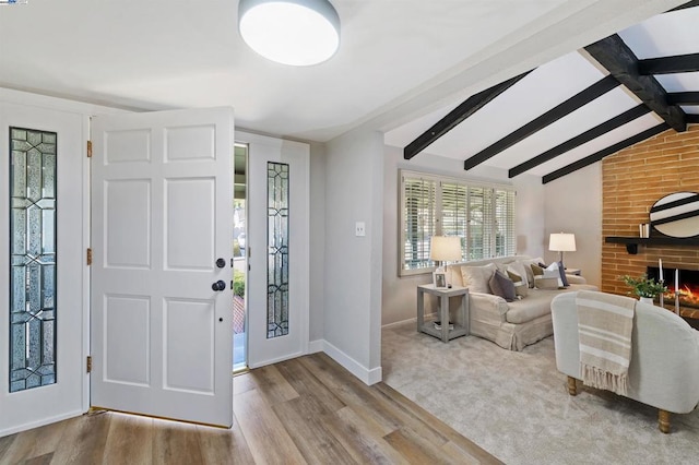 carpeted entrance foyer with a fireplace and lofted ceiling with beams