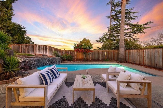 pool at dusk featuring an outdoor living space and a patio