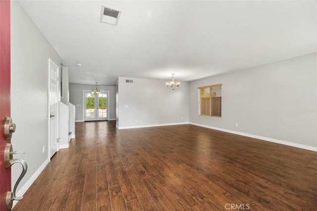 unfurnished living room featuring dark wood-type flooring and an inviting chandelier