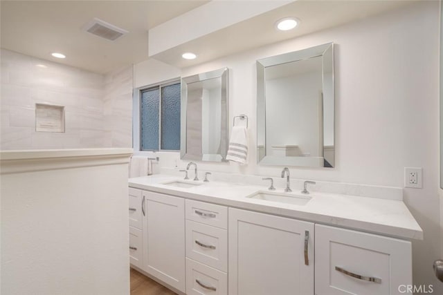 bathroom with a sink, double vanity, and recessed lighting