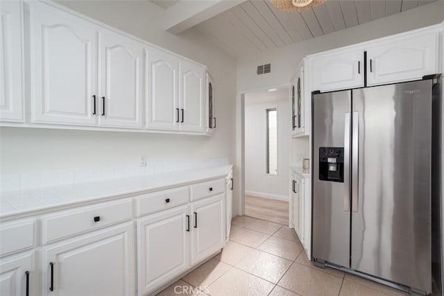 kitchen with stainless steel refrigerator with ice dispenser, white cabinetry, and light tile patterned floors