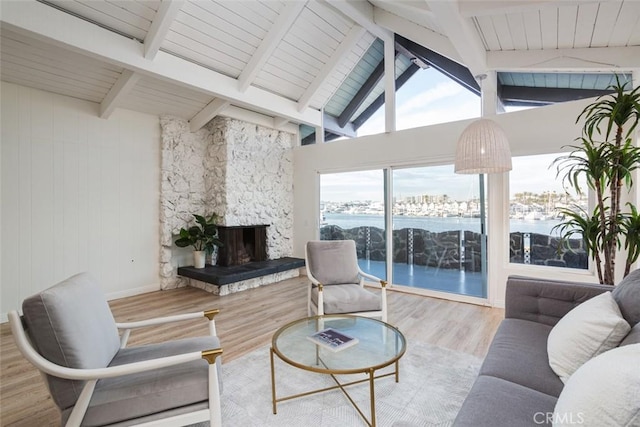 living room featuring beamed ceiling, a fireplace, high vaulted ceiling, a water view, and hardwood / wood-style flooring