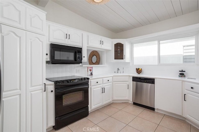 kitchen with vaulted ceiling, backsplash, white cabinetry, light tile patterned floors, and black appliances